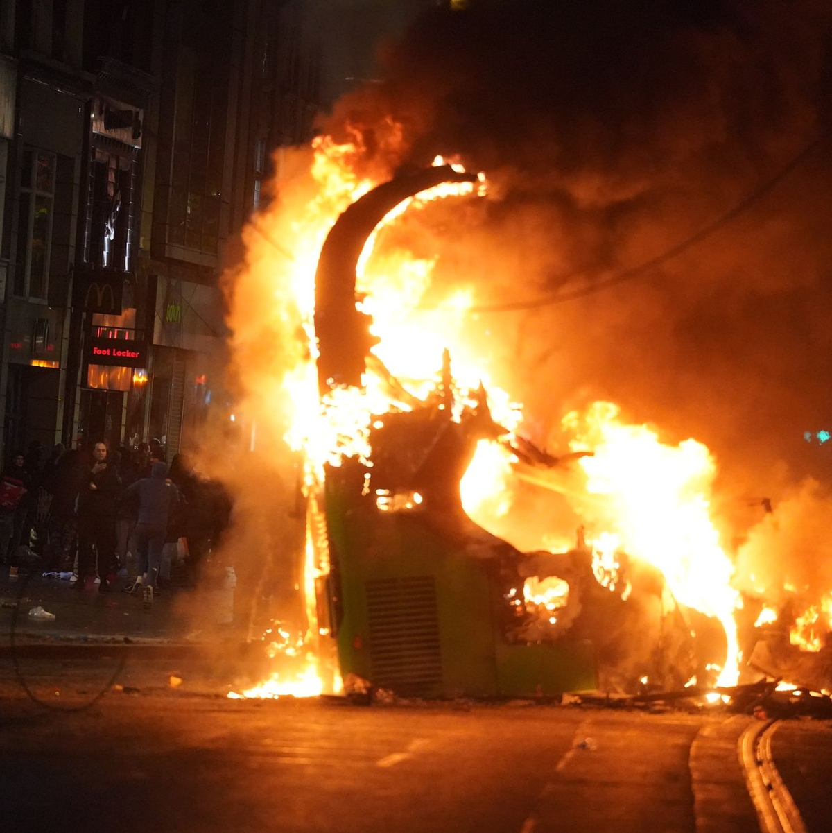 Ein Bus steht im Stadtzentrum in Flammen. - Foto: Brian Lawless/PA Wire/dpa
