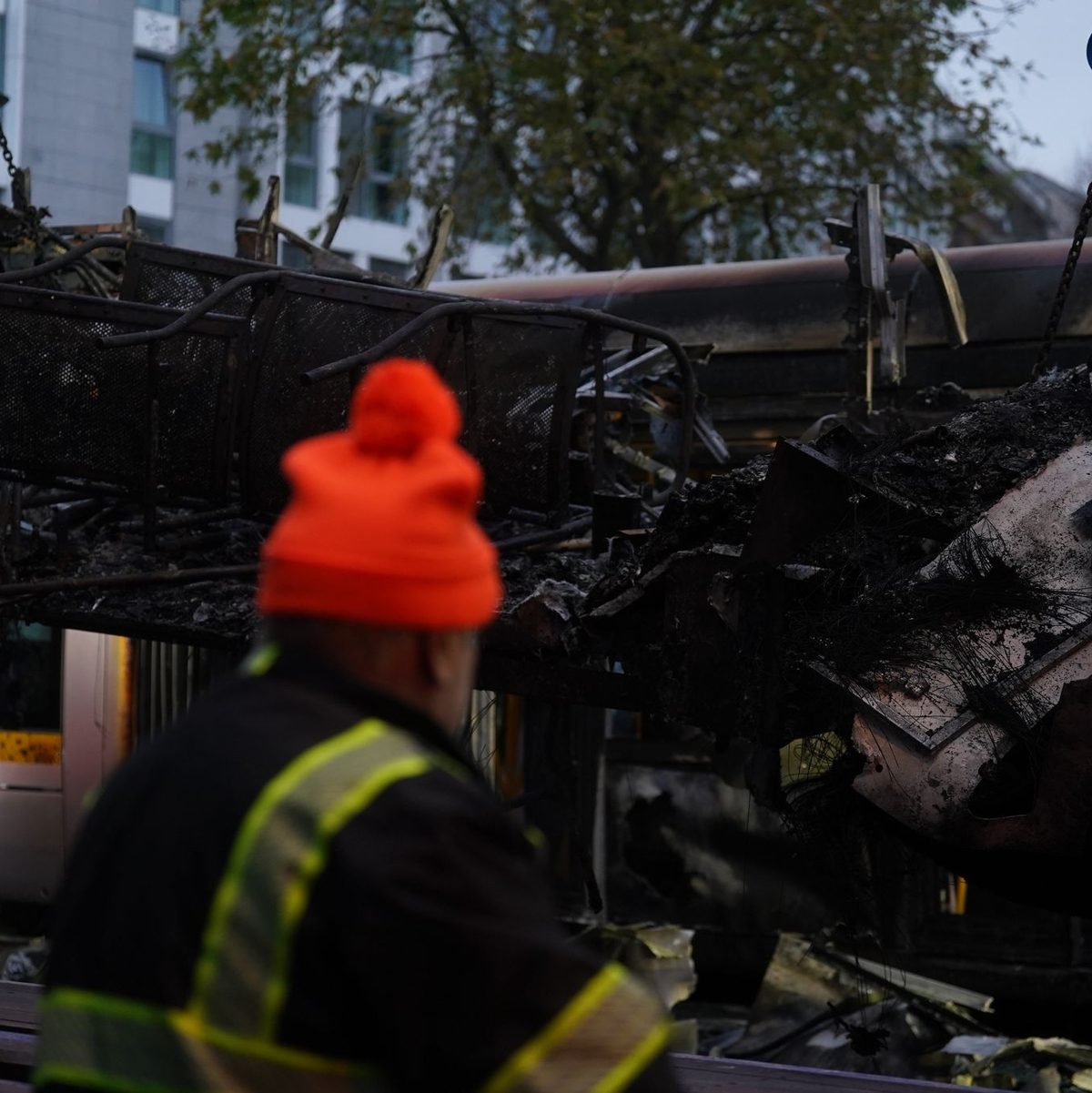 Spuren der Ausschreitungen in Dublin. Ein Arbeiter steht vor einer ausgebrannten Straßenbahn. - Foto: Brian Lawless/PA Wire/dpa