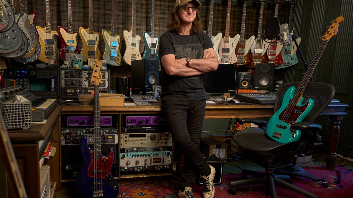Der Rush-Frontmann Geddy Lee steht in seinem Studio, Bassgitarren hängen an der Wand. - Foto: HarperCollins