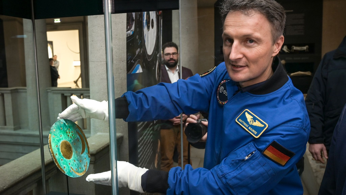 Der Astronaut Matthias Maurer platziert die Nachbildung der Himmelsscheibe von Nebra in einer Vitrine im Landesmuseum für Vorgeschichte Halle. - Foto: Heiko Rebsch/dpa