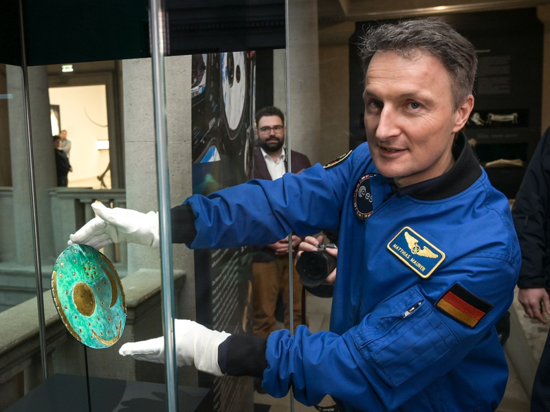 Der Astronaut Matthias Maurer platziert die Nachbildung der Himmelsscheibe von Nebra in einer Vitrine im Landesmuseum für Vorgeschichte Halle. - Foto: Heiko Rebsch/dpa
