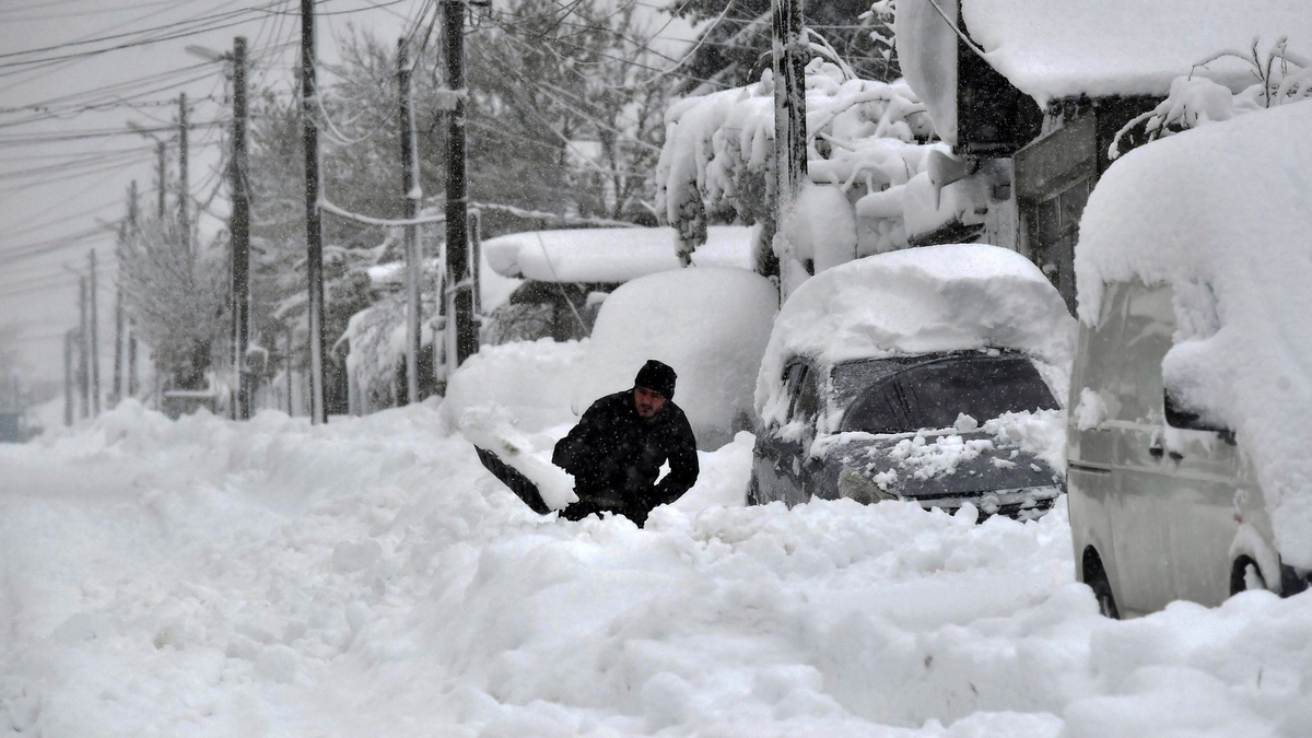 Ein Mann in Isperich schaufelt Schnee, um sein Auto zu befreien. - Foto: Mehmed Aziz/AP/dpa