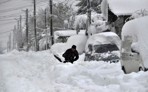 Ein Mann in Isperich schaufelt Schnee, um sein Auto zu befreien. - Foto: Mehmed Aziz/AP/dpa