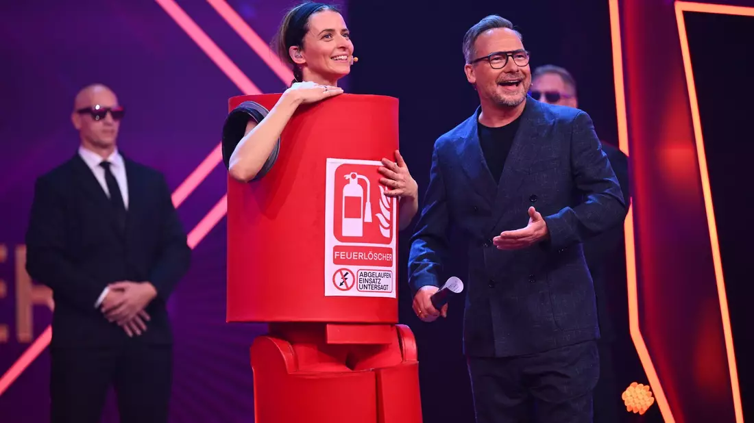 Model Eva Padberg ls „Der Feuerlöscher“ in der Prosieben-Show „The Masked Singer“ neben Moderator Matthias Opdenhövel. - Bild: Willi Weber/ProSieben/dpa