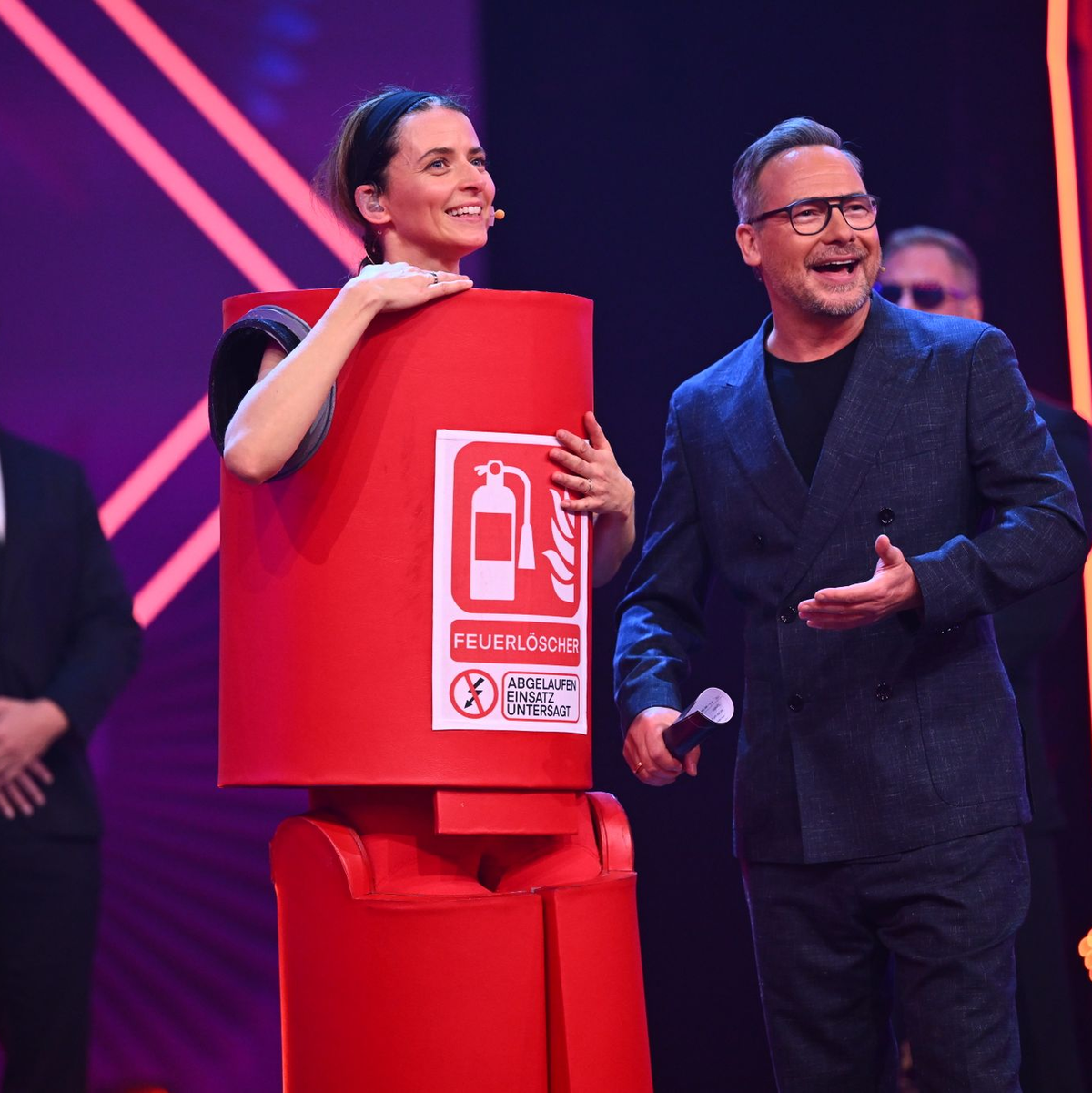 Model Eva Padberg ls „Der Feuerlöscher“ in der Prosieben-Show „The Masked Singer“ neben Moderator Matthias Opdenhövel. - Foto: Willi Weber/ProSieben/dpa