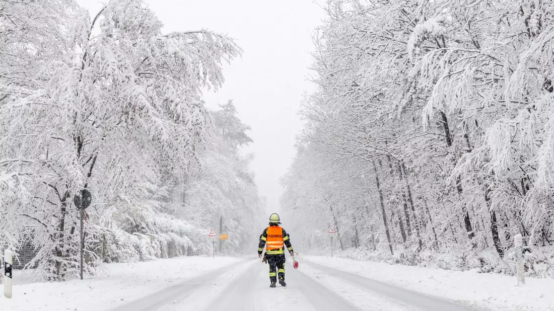 Ein Feuerwehrmann sperrt die Landstraße in Richtung Großer Feldberg (Taunus). - Bild: Jan Eifert/dpa