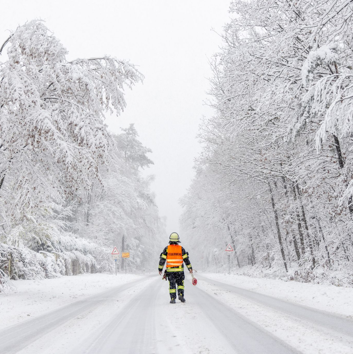 Ein Feuerwehrmann sperrt die Landstraße in Richtung Großer Feldberg (Taunus). - Foto: Jan Eifert/dpa