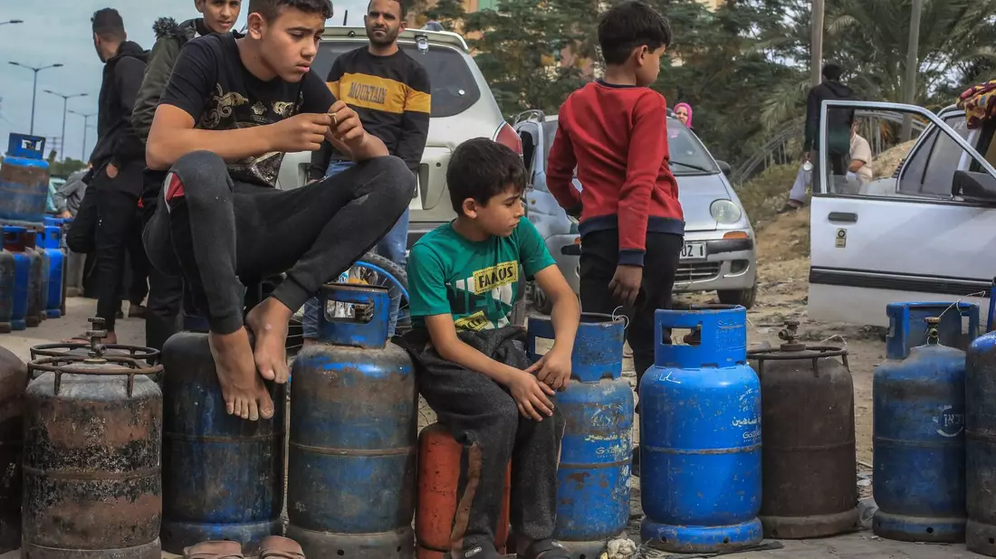 Palästinensische Kinder in Chan Junis stehen Schlange, um Flüssiggasflaschen aufzufüllen. - Bild: Mohammed Talatene/dpa