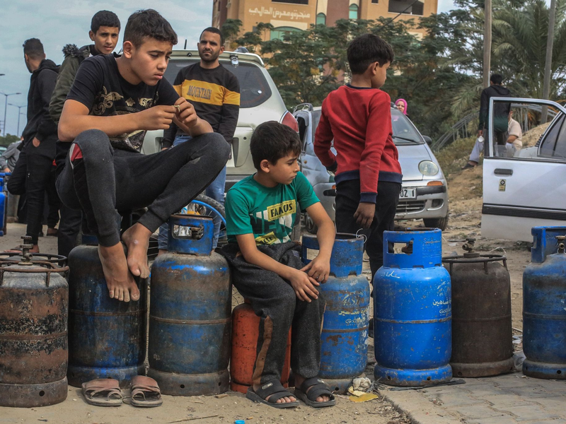Palästinensische Kinder in Chan Junis stehen Schlange, um Flüssiggasflaschen aufzufüllen. - Foto: Mohammed Talatene/dpa