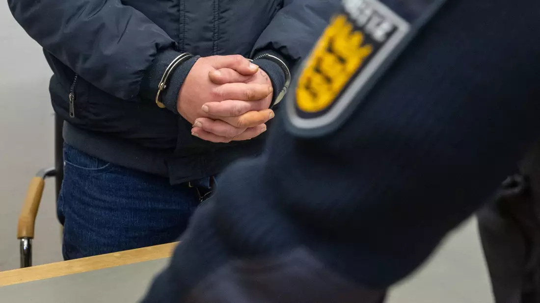 Der angeklagte 41-Jährige steht mit Handschellen im Landgericht. Er gab zu, im Frühjahr 2023 auf einem Schulhof seine siebenjährige Tochter ermordet zu haben. - Bild: Stefan Puchner/dpa