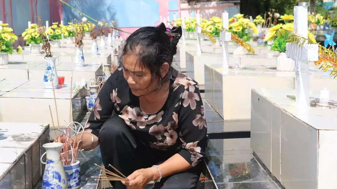 Nguyen Thi Nhiem zündet Räucherstäbchen auf einem Friedhof an und betet für die Seelen der ungeborenen Kinder. - Bild: Bac Pham/dpa