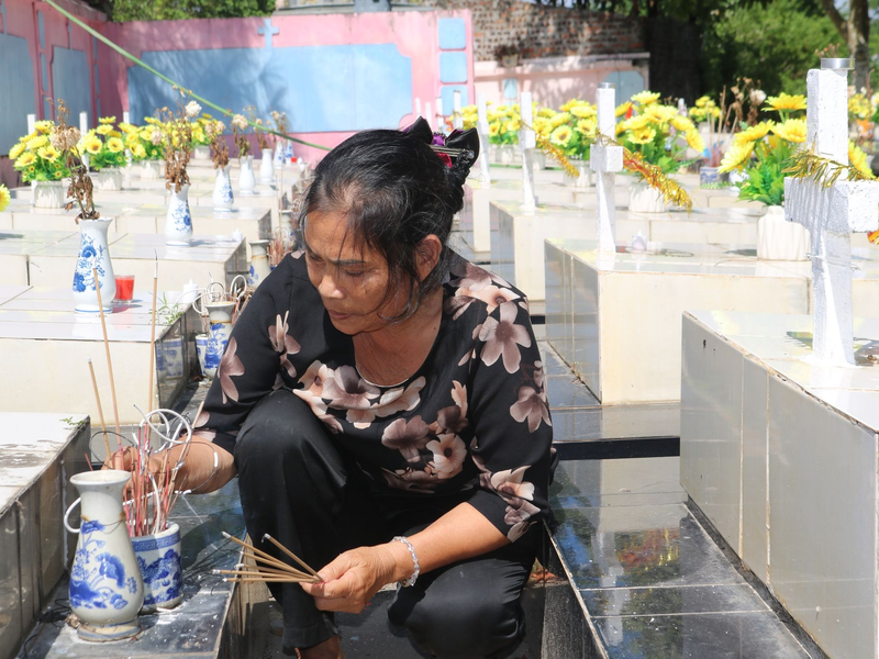 Nguyen Thi Nhiem zündet Räucherstäbchen auf einem Friedhof an und betet für die Seelen der ungeborenen Kinder. - Foto: Bac Pham/dpa