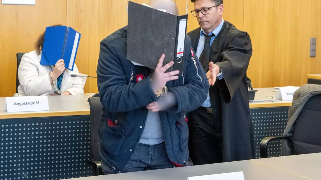 Im Landgericht weist ein Verteidiger seinem Klienten seinen Platz auf der Anklagebank. Dieser musste sich gemeinsam mit seiner Partnerin wegen Mordes verantworten. - Bild: Stefan Puchner/dpa