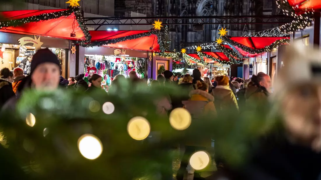 Der Weihnachtsmarkt am Kölner Dom ist am Abend gut besucht. - Bild: Christoph Reichwein/dpa