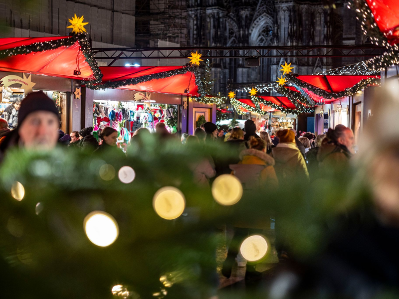 Der Weihnachtsmarkt am Kölner Dom ist am Abend gut besucht. - Foto: Christoph Reichwein/dpa