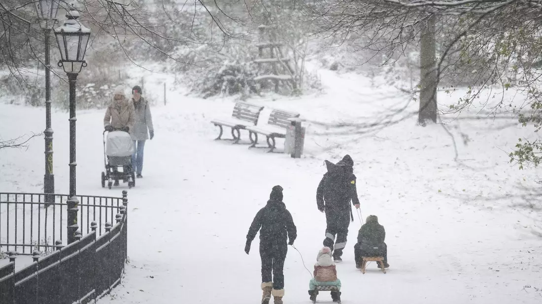 Menschen spazieren durch den verschneiten Volkspark Friedrichshain in Berlin. - Bild: Hannes P. Albert/dpa