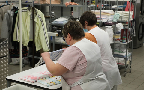Zwei Frauen arbeiten in der Wäscherei der Lebenshilfe Gera e.V und legen dort Wäsche zusammen. - Foto: Bodo Schackow/dpa-Zentralbild/dpa