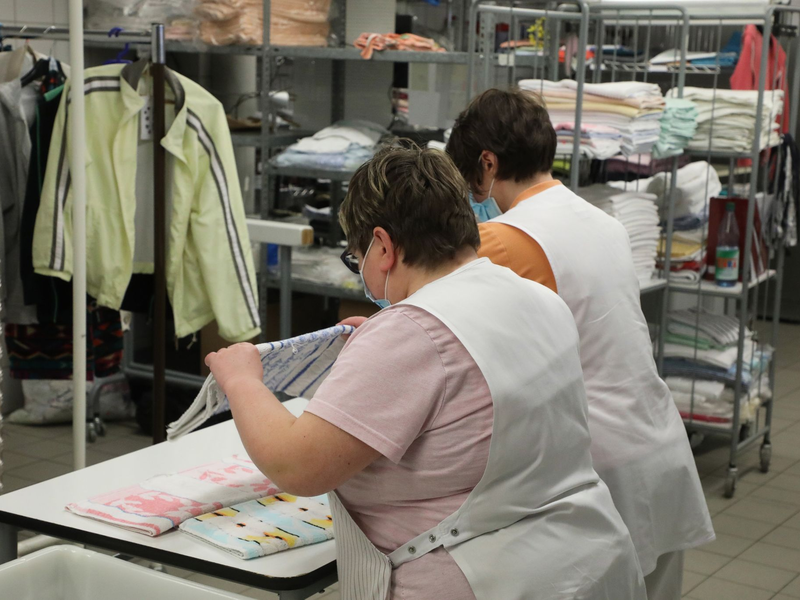 Zwei Frauen arbeiten in der Wäscherei der Lebenshilfe Gera e.V und legen dort Wäsche zusammen. - Foto: Bodo Schackow/dpa-Zentralbild/dpa