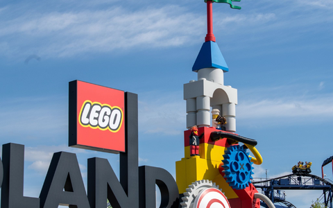 Neben dem Logo am Eingang zum Legoland ist eine Achterbahn zu sehen. - Foto: Stefan Puchner/dpa