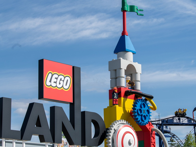 Neben dem Logo am Eingang zum Legoland ist eine Achterbahn zu sehen. - Foto: Stefan Puchner/dpa