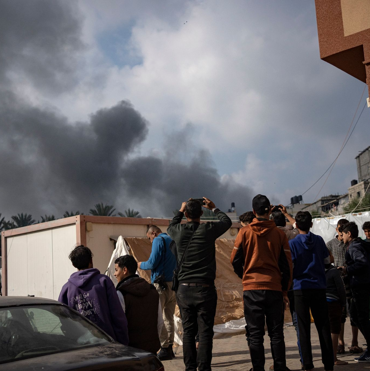 Palästinenser in Chan Junis betrachten den aufsteigenden Rauch nach einem israelischen Luftangriff. - Foto: Fatima Shbair/AP/dpa