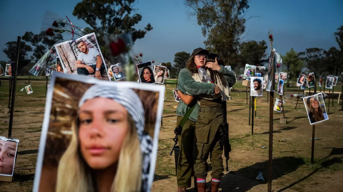 Israelische Soldatinnen stehen zwischen Fotos getöteter Israelis am Ort des Massakers beim Re'im-Musikfestival in der Negev-Wüste. - Bild: Ilia Yefimovich/dpa