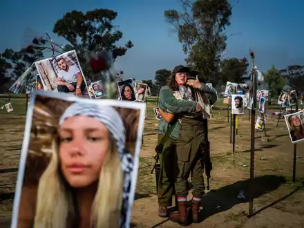 Israelische Soldatinnen stehen zwischen Fotos getöteter Israelis am Ort des Massakers beim Re'im-Musikfestival in der Negev-Wüste. - Foto: Ilia Yefimovich/dpa