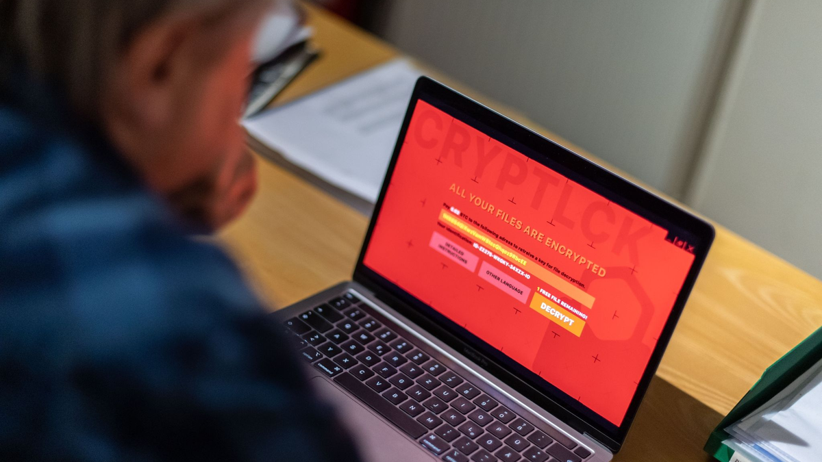 Ein Mann sitzt vor einem Laptop, der mit einem Verschlüsselungstrojaner (Ransomware) befallen ist. - Foto: Lino Mirgeler/dpa