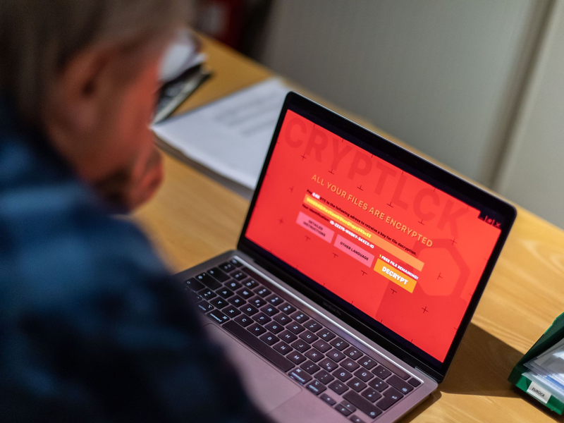 Ein Mann sitzt vor einem Laptop, der mit einem Verschlüsselungstrojaner (Ransomware) befallen ist. - Foto: Lino Mirgeler/dpa