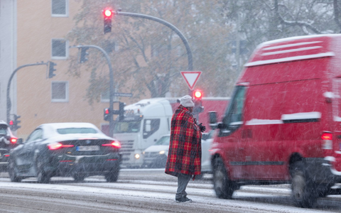 Zwischen wartenden Autos an der Ampel: Bitte um Almosen bei Schneetreiben in Hamburg. - Foto: Christian Charisius/dpa