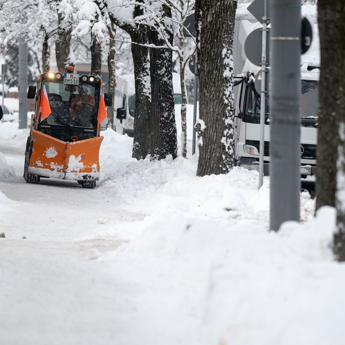 Ein Räumfahrzeug fährt über einen verschneiten Weg in München. - Foto: Lukas Barth/dpa
