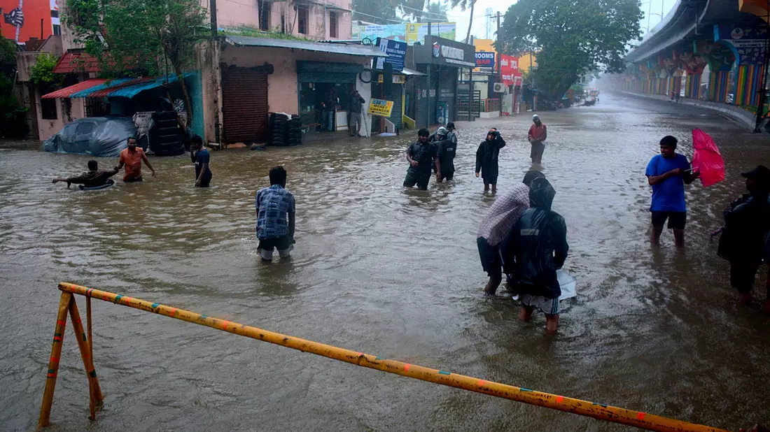 Menschen waten durch eine überschwemmte Straße nach heftigen Regenfällen an der Küste des Golfs von Bengalen. - Bild: Uncredited/AP