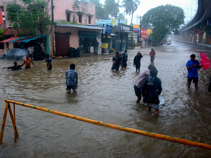 Menschen waten durch eine überschwemmte Straße nach heftigen Regenfällen an der Küste des Golfs von Bengalen. - Foto: Uncredited/AP