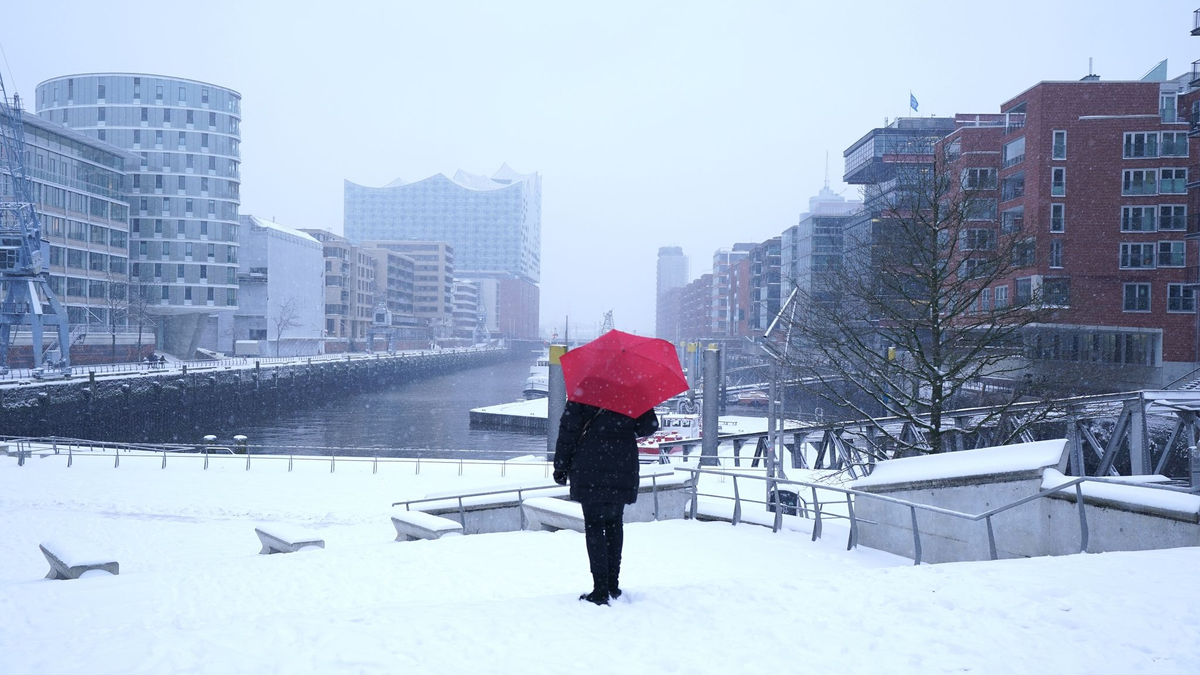 Eine Frau fährt mit einem Lastenfahrrad in Hamburg über eine verschneite Straße. - Foto: Marcus Brandt/dpa