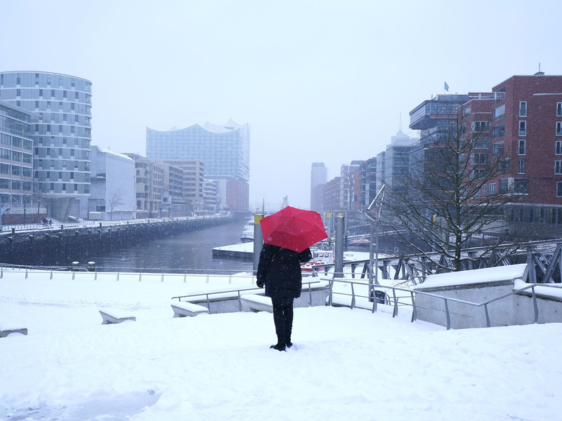 Eine Frau fährt mit einem Lastenfahrrad in Hamburg über eine verschneite Straße. - Foto: Marcus Brandt/dpa