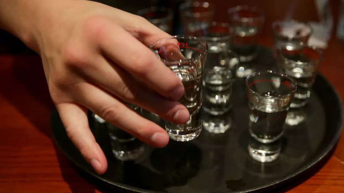 Eine Person greift nach einem gefüllten Schnapsglas. Mehr als zehn Millionen Menschen sterben laut der Weltgesundheitsorganisation (WHO) jedes Jahr durch Alkoholkonsum oder ungesunde Ernährung. - Bild: Axel Heimken/dpa