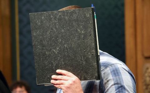 Der angeklagte Feuerwehrmann mit einem Aktendeckel vor dem Gesicht im Gerichtssaal. - Foto: Bernd Wüstneck/dpa