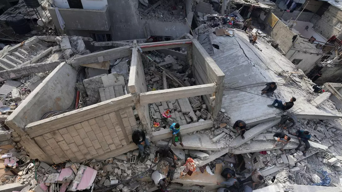 Palästinenser suchen in einem zerstörten Flüchtlingslager im Zentrum des Gazastreifens nach Leichen. - Bild: Adel Hana/AP/dpa