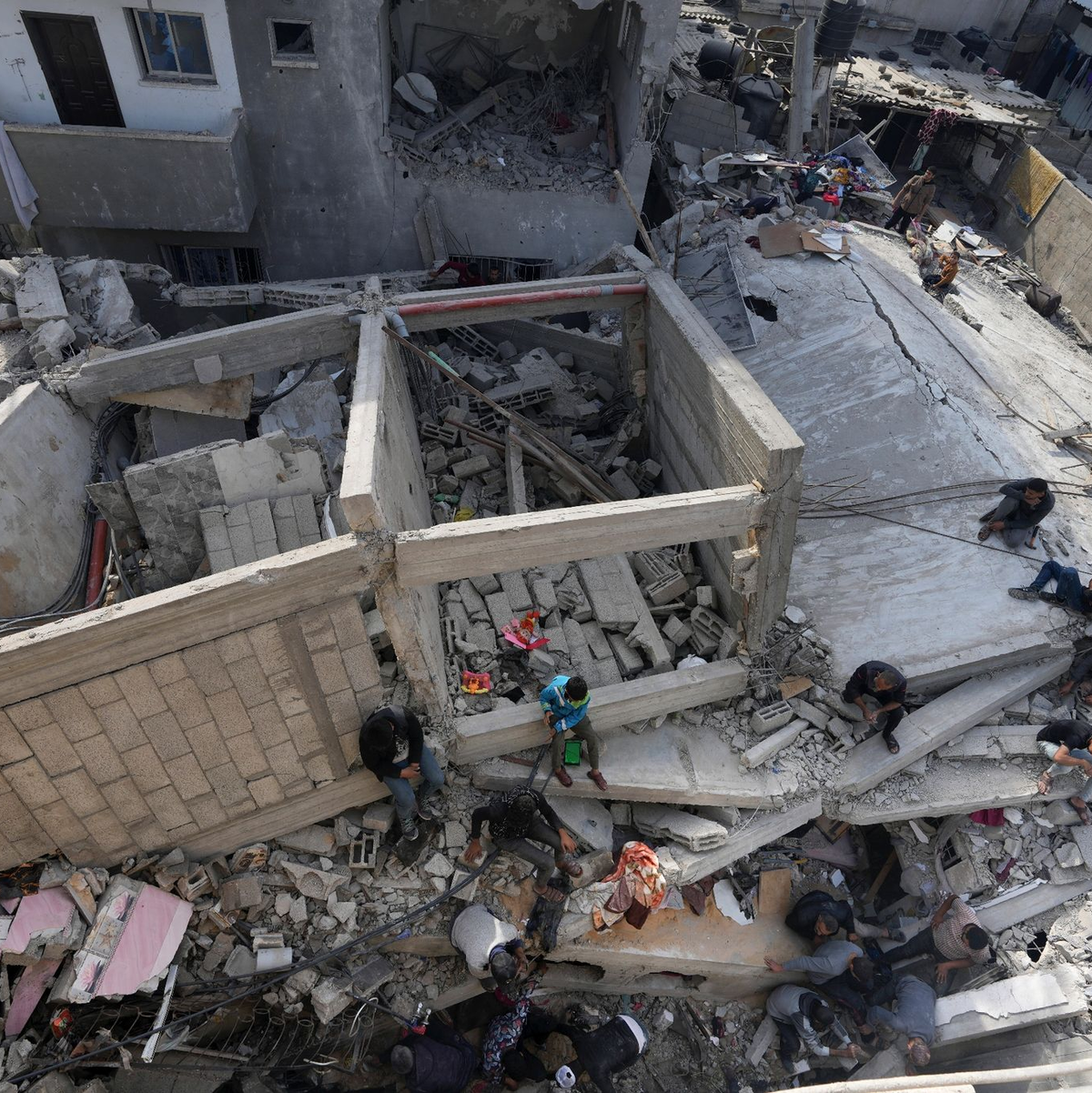 Palästinenser suchen in einem zerstörten Flüchtlingslager im Zentrum des Gazastreifens nach Leichen. - Foto: Adel Hana/AP/dpa