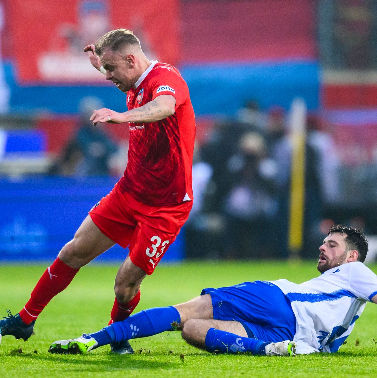 Schlagabtausch im Aufsteiger-Duell: Heidenheims Lennard Maloney (l) im Duell gegen Luca Pfeiffer (r) aus Darmstadt. - Foto: Tom Weller/dpa