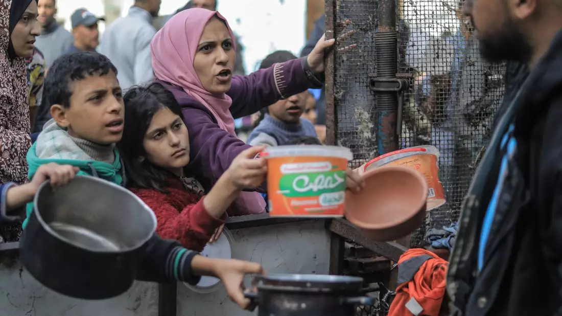 Menschen bitten an einer Essensausgabe in Rafah um Lebensmittel. - Bild: Mohammed Talatene/dpa