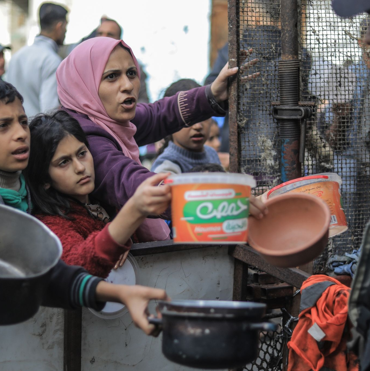 Menschen bitten an einer Essensausgabe in Rafah um Lebensmittel. - Foto: Mohammed Talatene/dpa