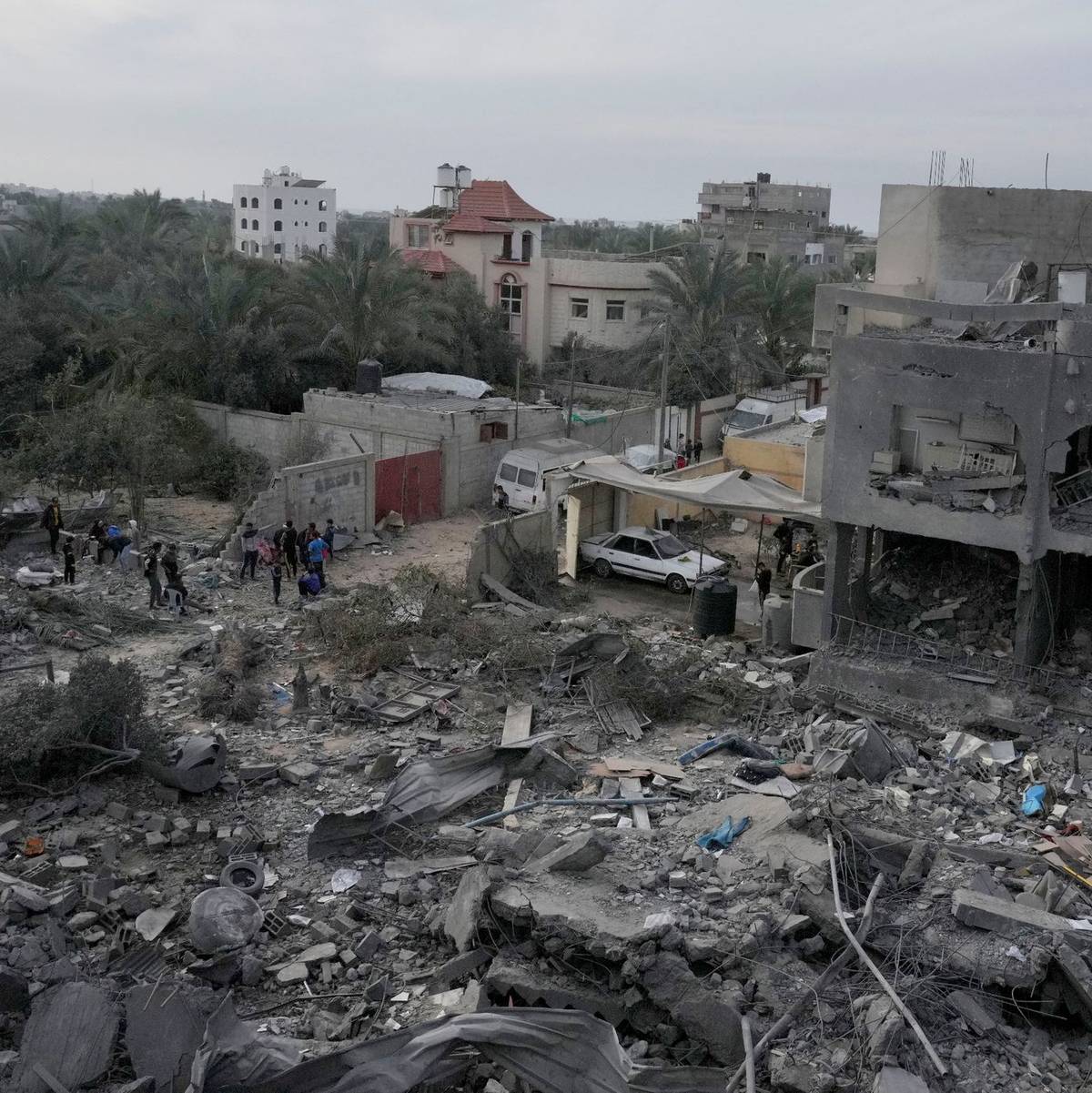 Palästinenser betrachten die Trümmer eines Gebäudes im Zenrum des Gazastreifens, das bei einer israelischen Bombardierung zerstört wurde. - Foto: Hatem Moussa/AP/dpa