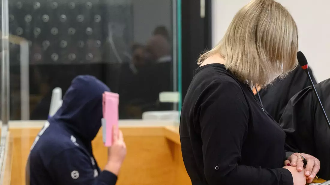 Die angeklagte Mutter und ihr Lebensgefährte warten im Gerichtsaal. - Bild: Julian Stratenschulte/dpa