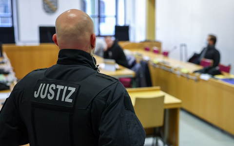 Ein Justizbeamter steht vor Prozessbeginn vor einigen Angeklagten im Landgericht Chemnitz. - Foto: Jan Woitas/dpa