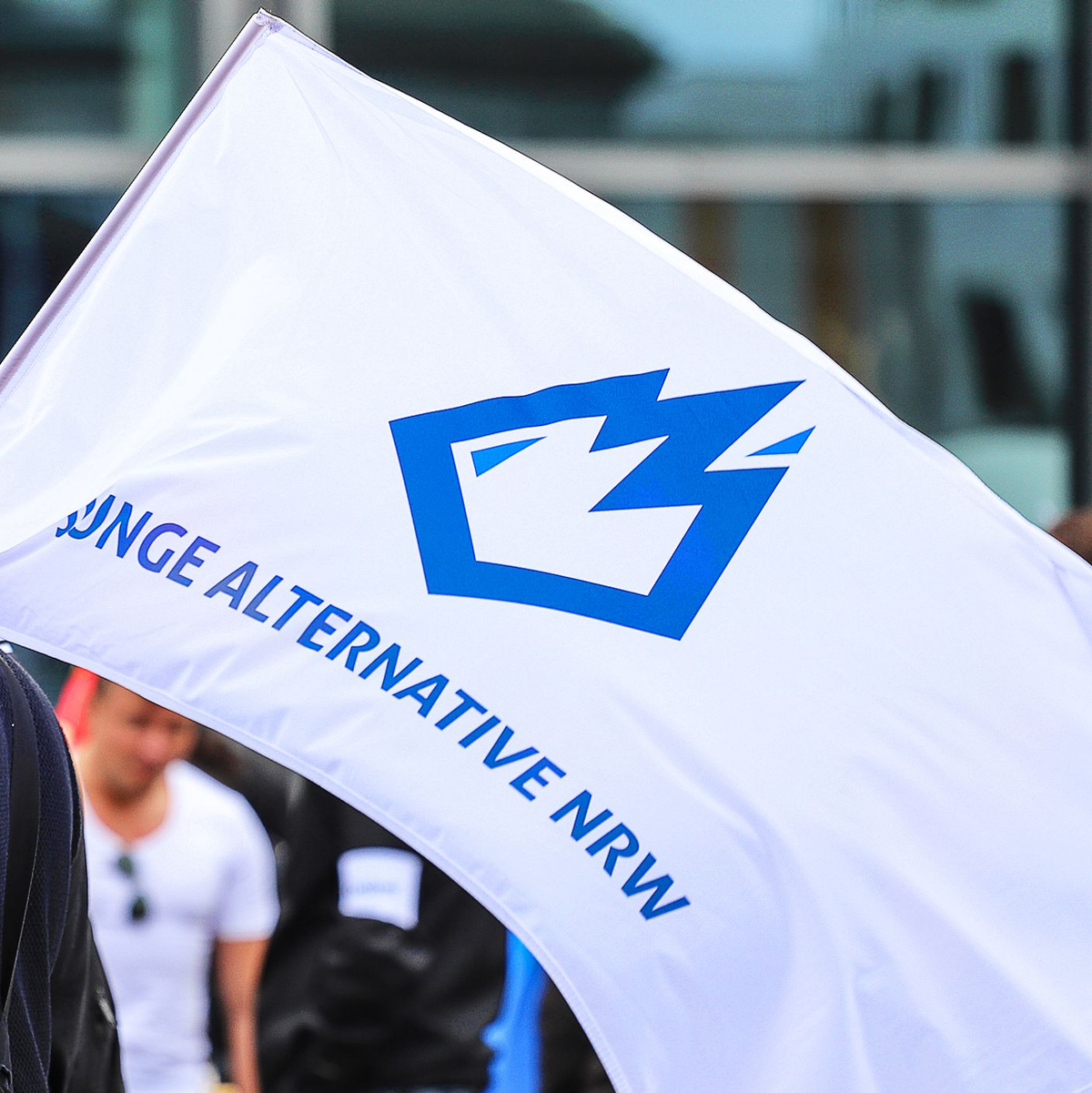 Ein Mitglied der «Jungen Alternative» (JA) trägt auf einer Wahlkampfveranstaltung in Dortmund eine Fahne mit dem Logo der Organisation. - Foto: Alex Talash/dpa