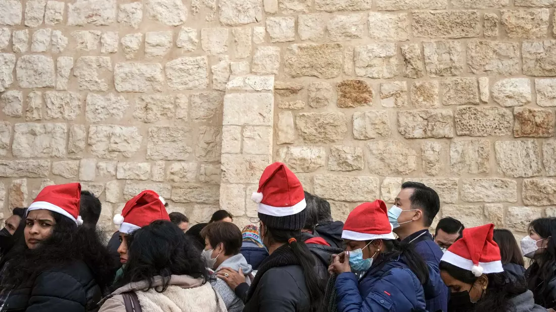 Heiligabend im vergangenen Jahr: Touristen - einige mit Weihnachtsmützen - stehen in Bethlehem vor der Geburtskirche Schlange. - Bild: Maya Alleruzzo/AP/dpa