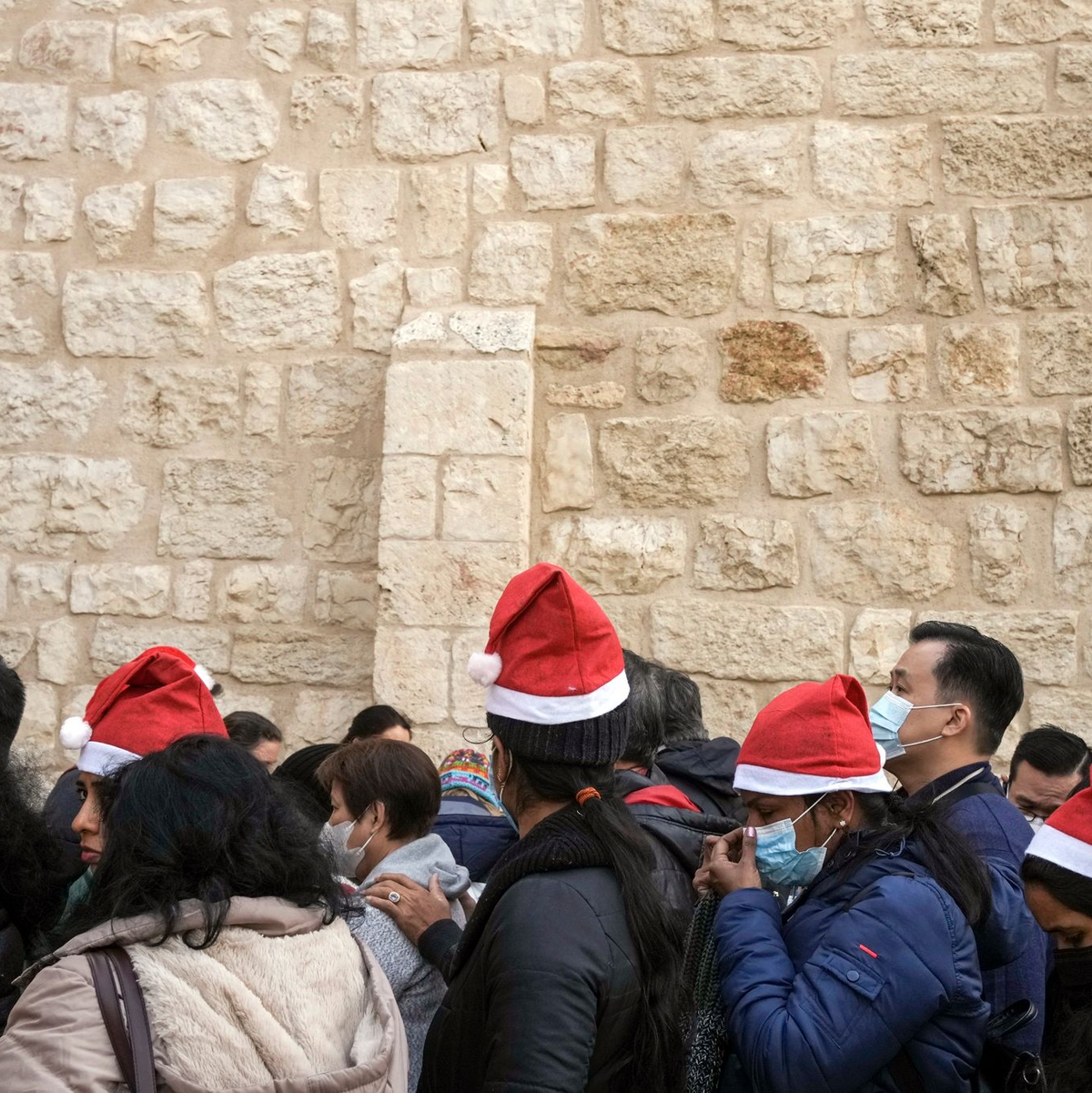 Heiligabend im vergangenen Jahr: Touristen - einige mit Weihnachtsmützen - stehen in Bethlehem vor der Geburtskirche Schlange. - Foto: Maya Alleruzzo/AP/dpa