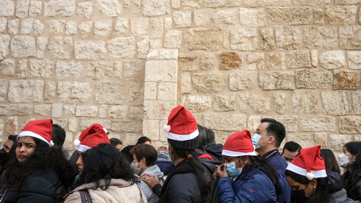 Heiligabend im vergangenen Jahr: Touristen - einige mit Weihnachtsmützen - stehen in Bethlehem vor der Geburtskirche Schlange. - Foto: Maya Alleruzzo/AP/dpa
