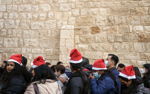 Heiligabend im vergangenen Jahr: Touristen - einige mit Weihnachtsmützen - stehen in Bethlehem vor der Geburtskirche Schlange. - Foto: Maya Alleruzzo/AP/dpa
